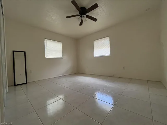 Unfurnished room featuring a textured ceiling, light tile patterned flooring, and ceiling fan