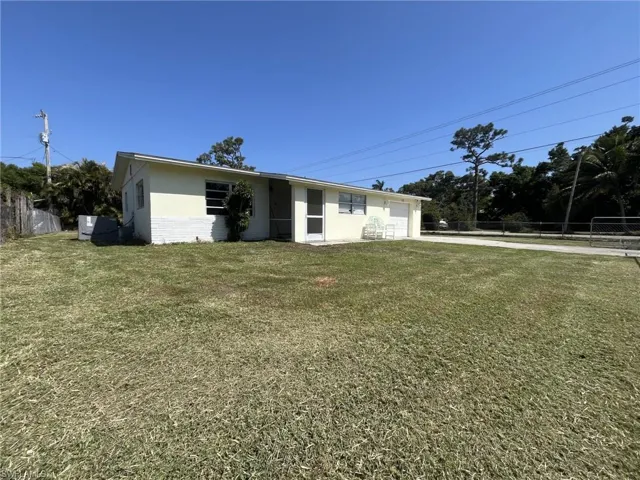 View of front facade with a front yard, fence, a garage, and driveway