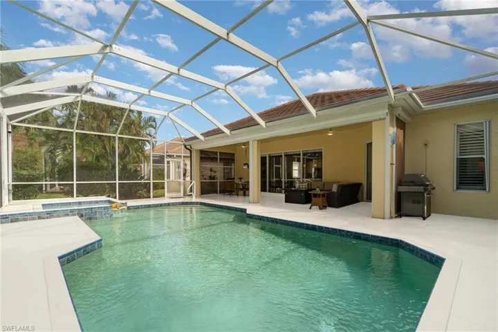 View of pool with grilling area, an in ground hot tub, a patio, glass enclosure, and ceiling fan