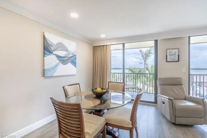 Dining area featuring light hardwood / wood-style flooring, floor to ceiling windows, ornamental molding, and a water view