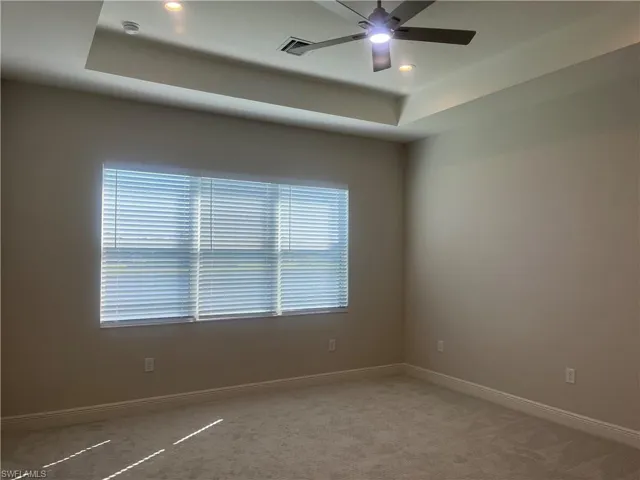 Unfurnished room featuring a tray ceiling, a ceiling fan, carpet floors, and recessed lighting