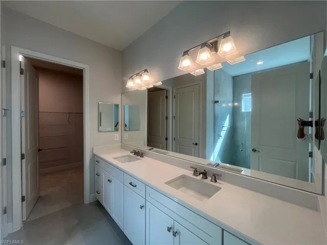 Bathroom with double vanity, a stall shower, and a walk in closet