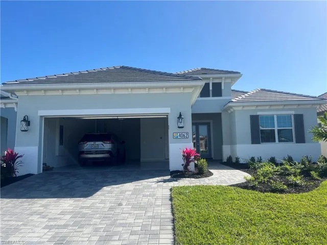 View of front facade featuring an attached garage, a tiled roof, decorative driveway, and stucco siding