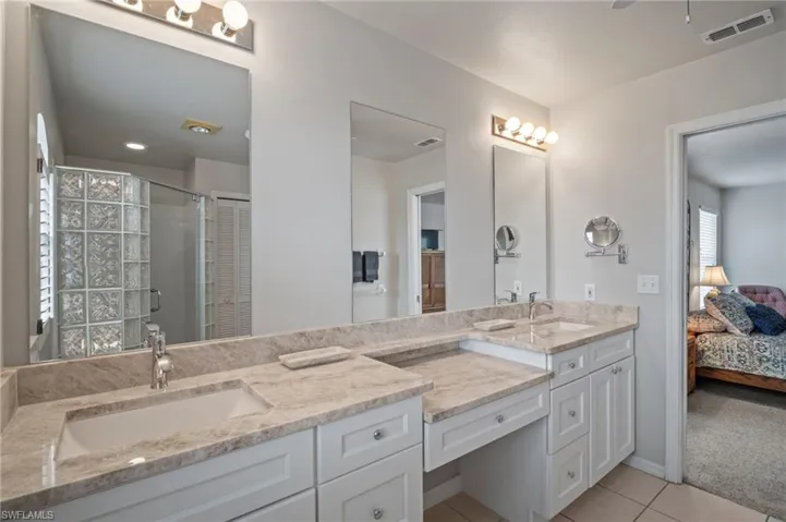 Ensuite bathroom featuring vanity, light tile patterned flooring, and a shower stall