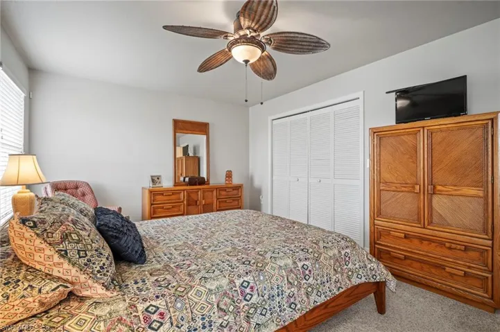 Carpeted bedroom featuring a ceiling fan and a closet
