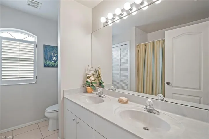 Bathroom featuring light tile patterned floors, double vanity, and a closet