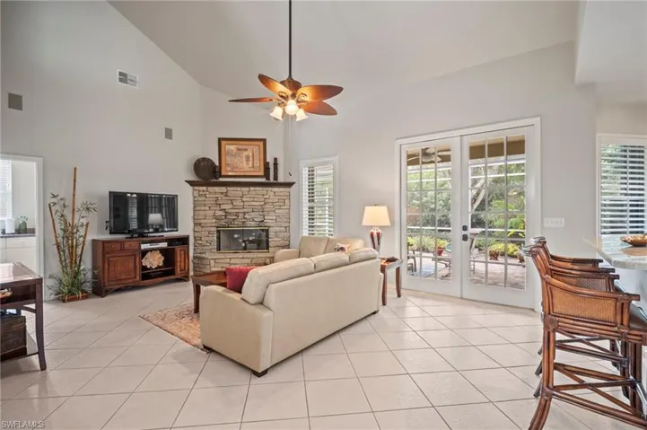 Living area with light tile patterned flooring, french doors, high vaulted ceiling, a fireplace, and ceiling fan