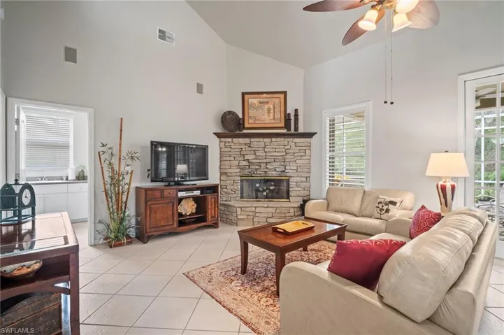 Living area featuring ceiling fan, high vaulted ceiling, light tile patterned floors, and a fireplace