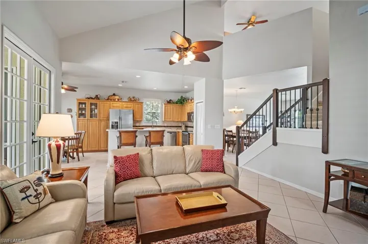 Living room with ceiling fan, light tile patterned floors, high vaulted ceiling, stairs, and recessed lighting