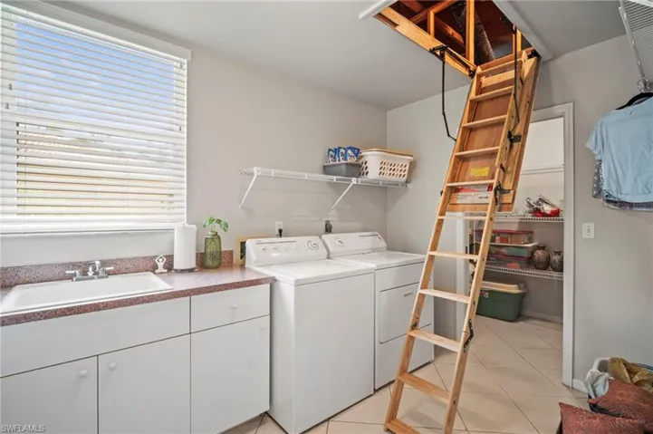 Laundry room featuring light tile patterned floors, independent washer and dryer, and cabinet space