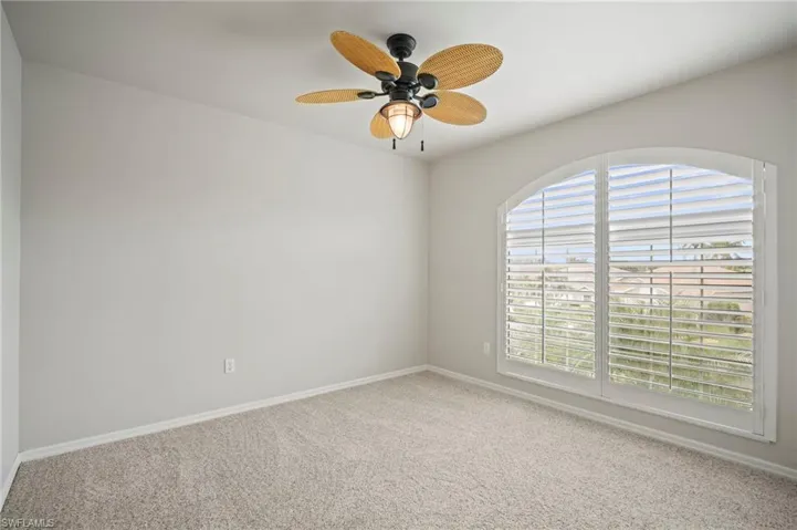 Carpeted empty room with a ceiling fan and baseboards
