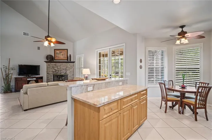 Kitchen with ceiling fan, light stone countertops, light tile patterned floors, and high vaulted ceiling
