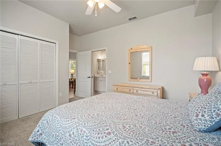 Bedroom featuring light carpet, a closet, a ceiling fan, and ensuite bath