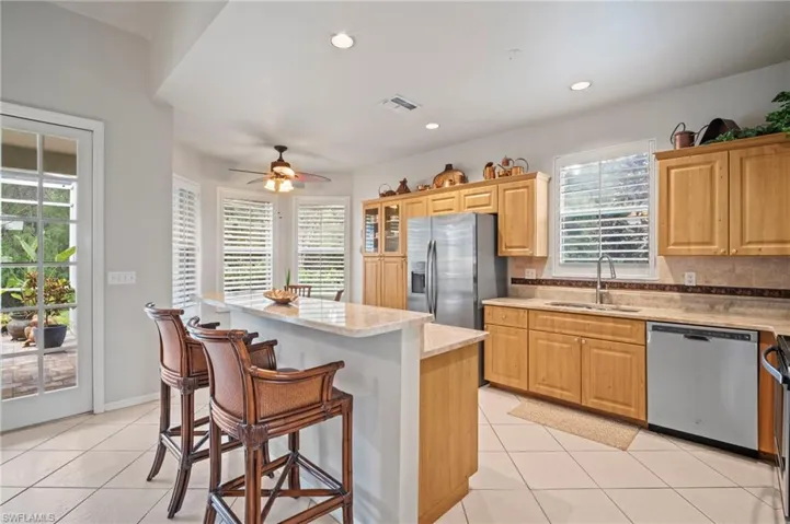 Kitchen featuring light tile patterned floors, tasteful backsplash, stainless steel appliances, a breakfast bar area, and recessed lighting