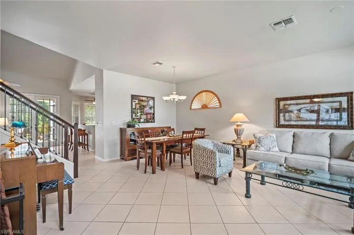 Living room with stairway, light tile patterned floors, and a chandelier