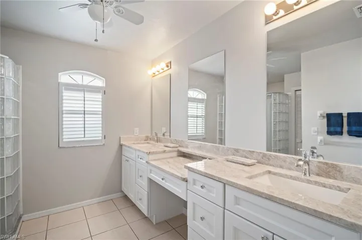 Bathroom featuring a ceiling fan, double vanity, plenty of natural light, and light tile patterned floors