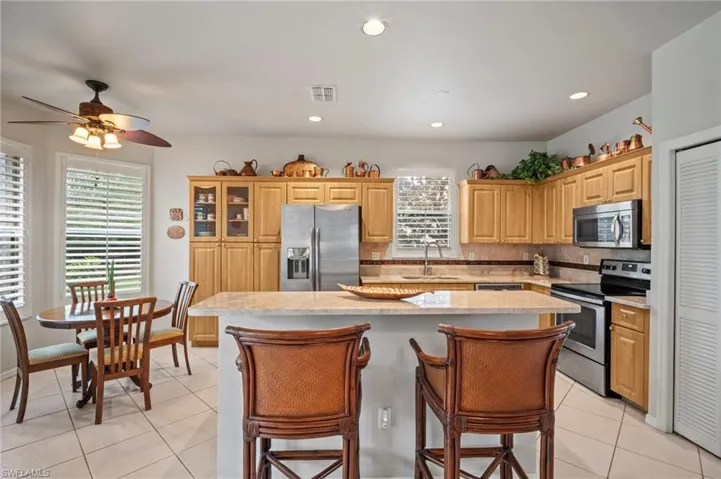 Kitchen with a kitchen bar, appliances with stainless steel finishes, light tile patterned floors, a kitchen island, and decorative backsplash