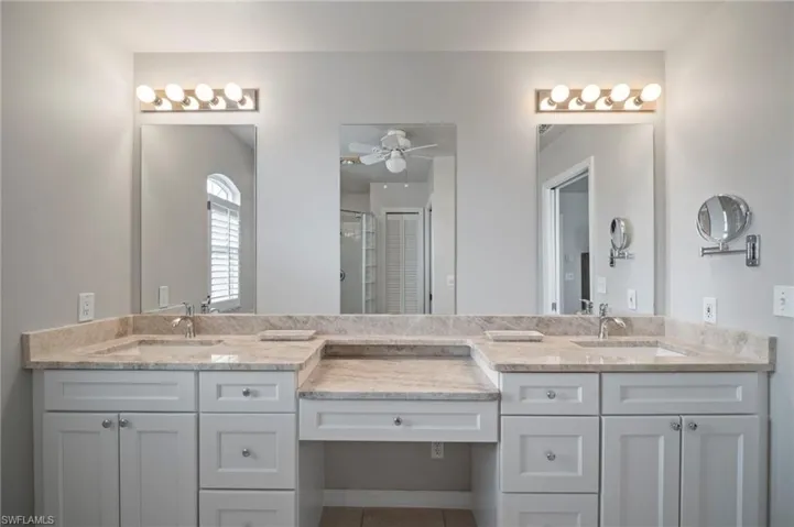 Full bath featuring two vanities, a shower stall, ceiling fan, and tile patterned floors