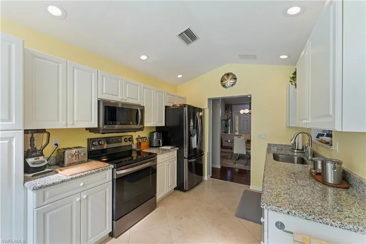 Kitchen with white cabinetry, lofted ceiling, appliances with new stainless steel appliances, and sink