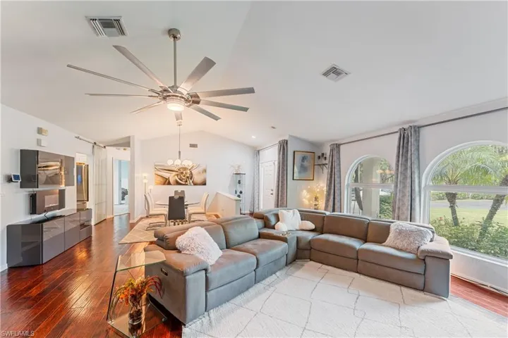 Living room featuring lofted ceiling, wood-type flooring, and ceiling fan