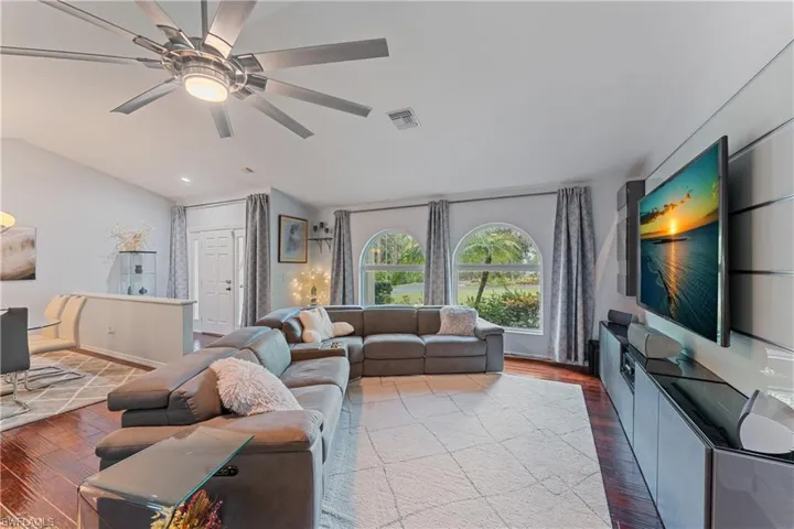 Living room featuring lofted ceiling, wood-type flooring, and ceiling fan