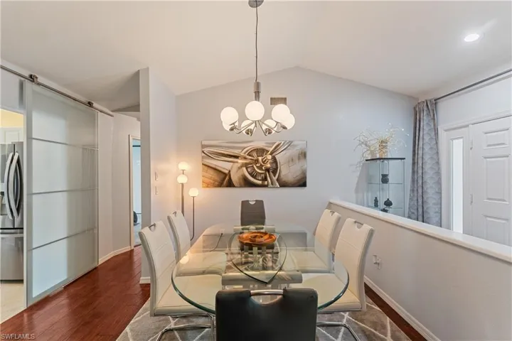 Dining area with an inviting chandelier, lofted ceiling, and dark hardwood / wood-style floors