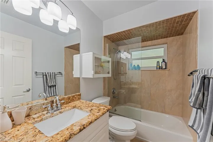 Full bathroom with tiled shower / bath, vanity, and toilet