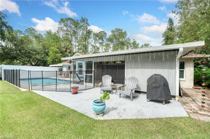Rear view of house featuring a fenced in pool, a patio area, and a lawn