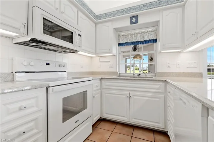 Kitchen with white appliances, tasteful backsplash, and white cabinetry