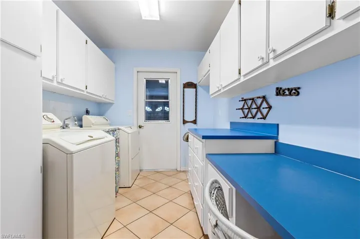 Washroom with washer and dryer, cabinet space, and light tile patterned floors