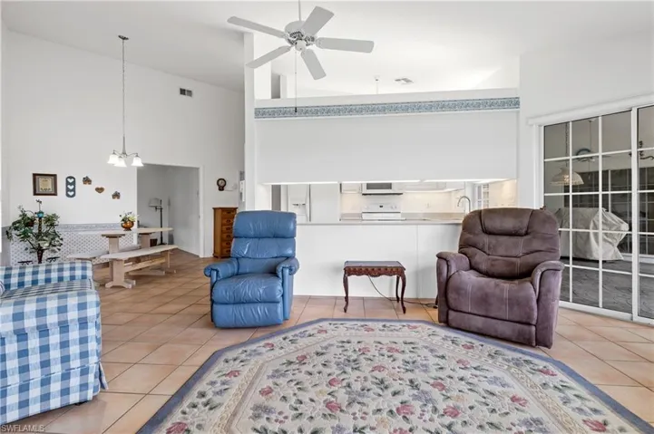 Tiled living room featuring a high ceiling, a ceiling fan, and a chandelier