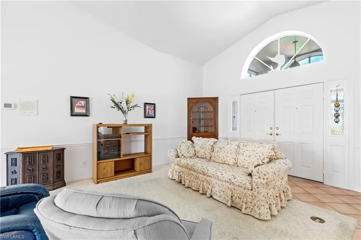 Living area featuring high vaulted ceiling and tile patterned flooring