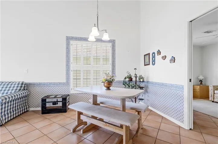 Dining room featuring wallpapered walls, light tile patterned flooring, a chandelier, and wainscoting