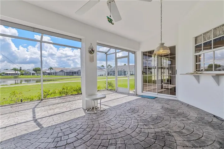 Unfurnished sunroom with a water view, ceiling fan, a residential view, and lofted ceiling