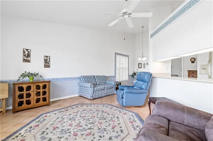Tiled living room with a towering ceiling and a ceiling fan