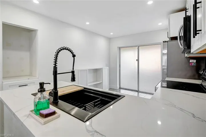Kitchen featuring light stone counters, recessed lighting, white cabinetry, and appliances with stainless steel finishes