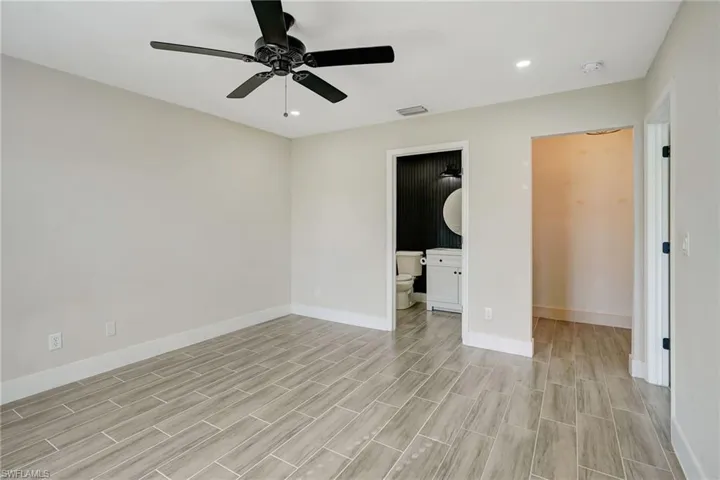 Unfurnished bedroom with wood tiled floors, ceiling fan, recessed lighting, and connected bathroom