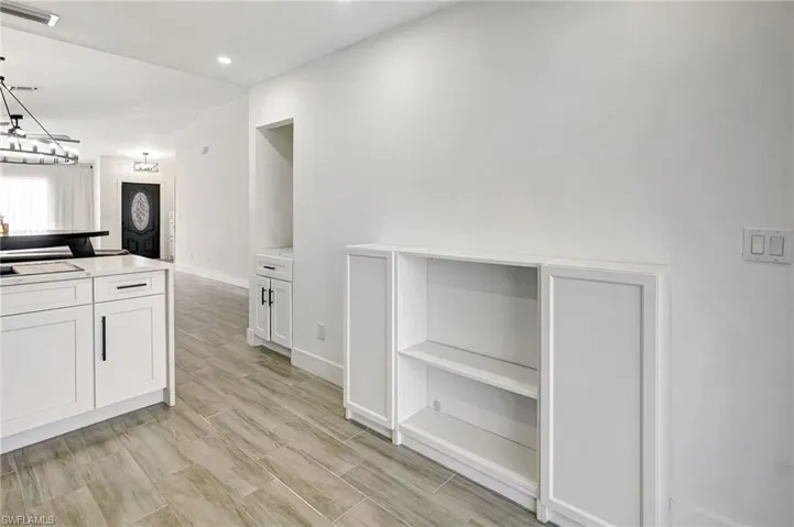 Kitchen featuring white cabinets, recessed lighting, wood tiled floors, and decorative light fixtures