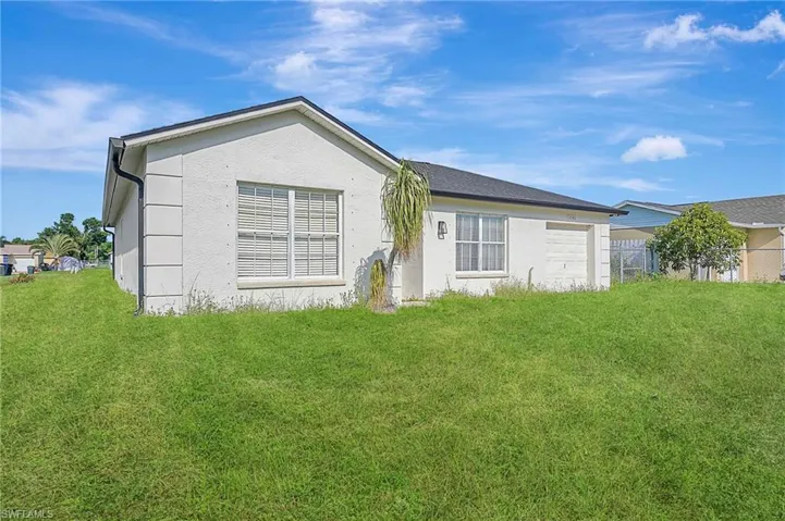 Back of property featuring a lawn and stucco siding