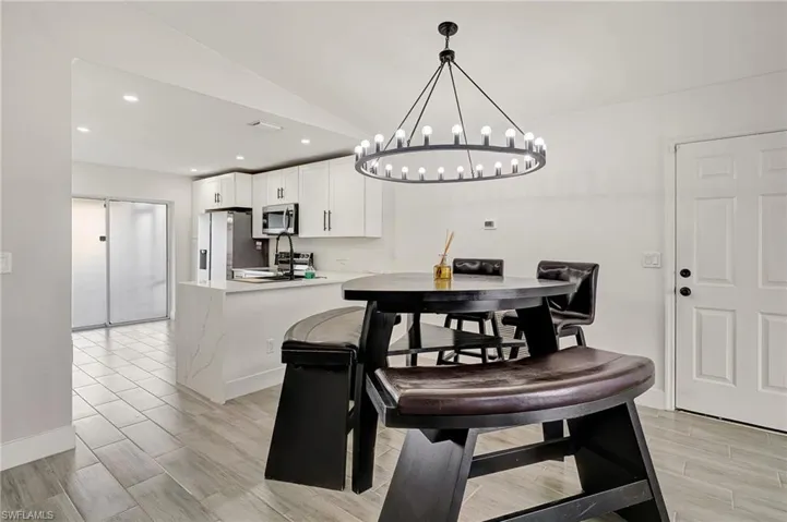 Dining area featuring wood finish floors, recessed lighting, vaulted ceiling, and a chandelier