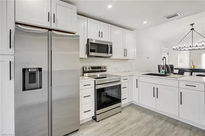 Kitchen with appliances with stainless steel finishes, white cabinets, recessed lighting, a chandelier, and decorative light fixtures