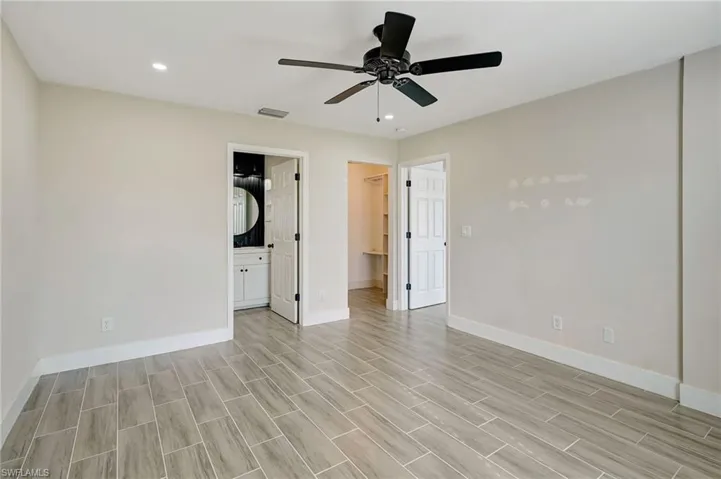 Unfurnished bedroom with a spacious closet, ceiling fan, wood tiled floors, recessed lighting, and connected bathroom