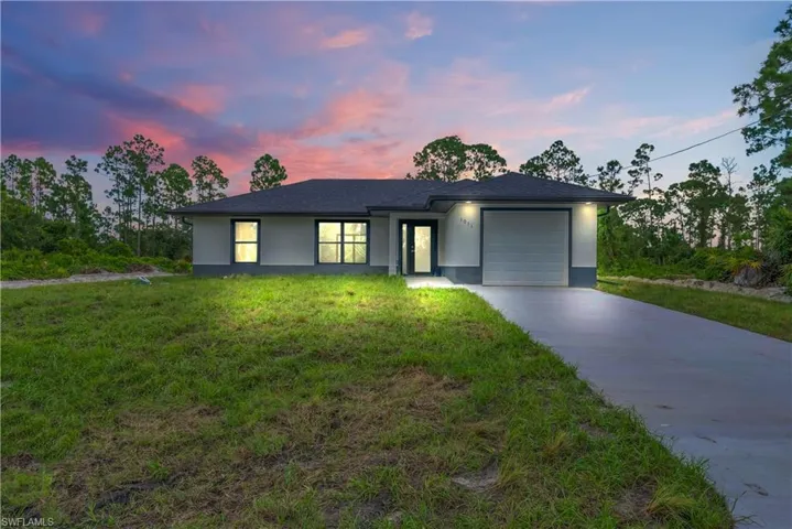 View of front of house featuring an attached garage, driveway, stucco siding, a lawn, and roof with shingles