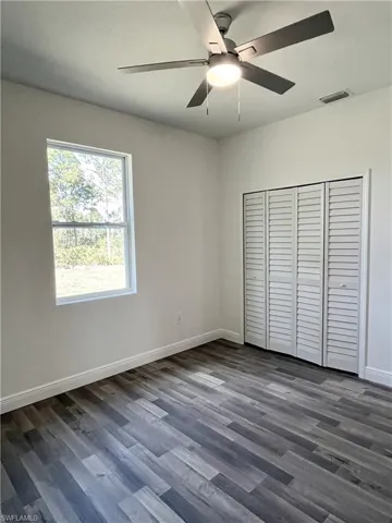 Unfurnished bedroom featuring ceiling fan, a closet, and dark hardwood / wood-style floors