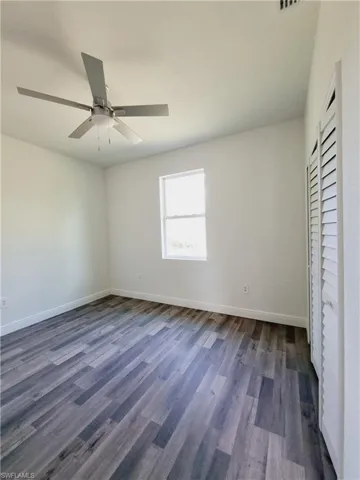 Unfurnished bedroom with ceiling fan and dark wood-type flooring