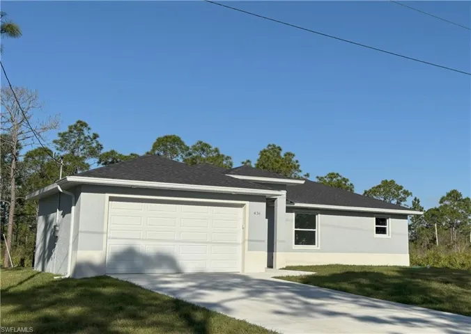 Ranch-style home with a front yard, a garage, driveway, and stucco siding