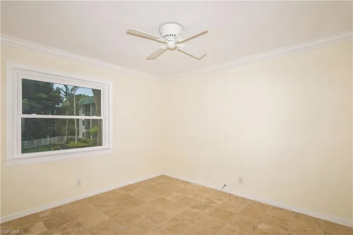 Spare room featuring crown molding, ceiling fan, and light tile floors