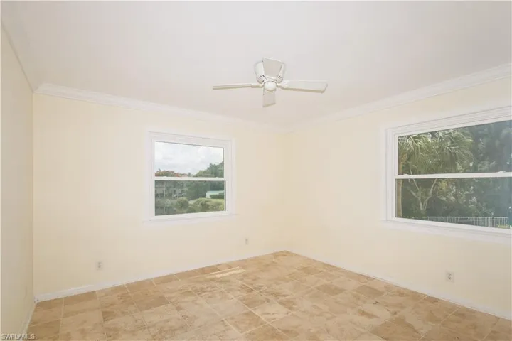 Spare room featuring ornamental molding, ceiling fan, and light tile floors