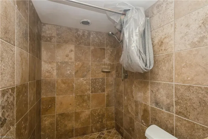 master Bathroom with tiled shower and toilet