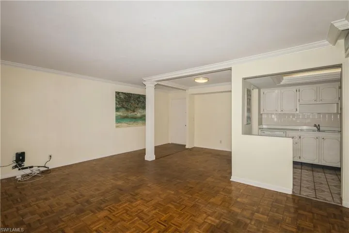 Unfurnished living room featuring dark parquet floors and ornamental molding